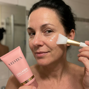 Vrouw brengt met het siliconen kwastje een egale laag masker aan op haar wang